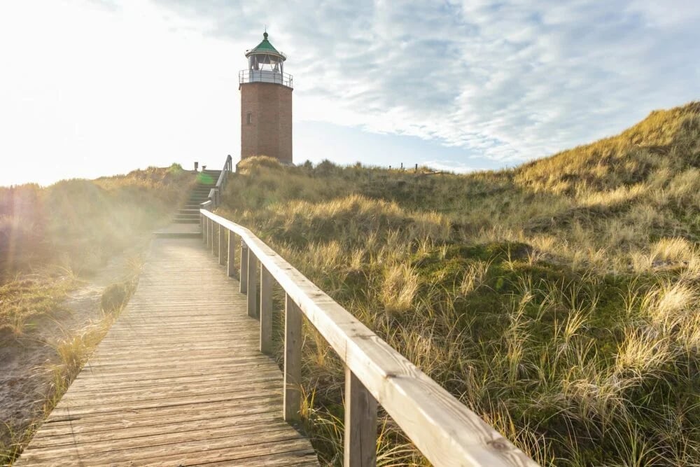 a wooden walkway leading to a lighthouse on a hill